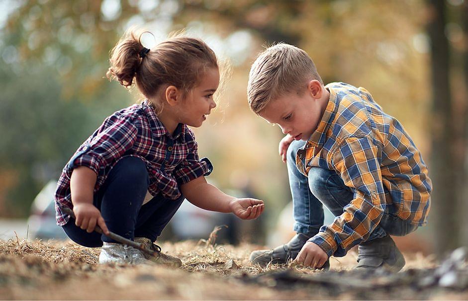 Young children playing outdoors with sticks